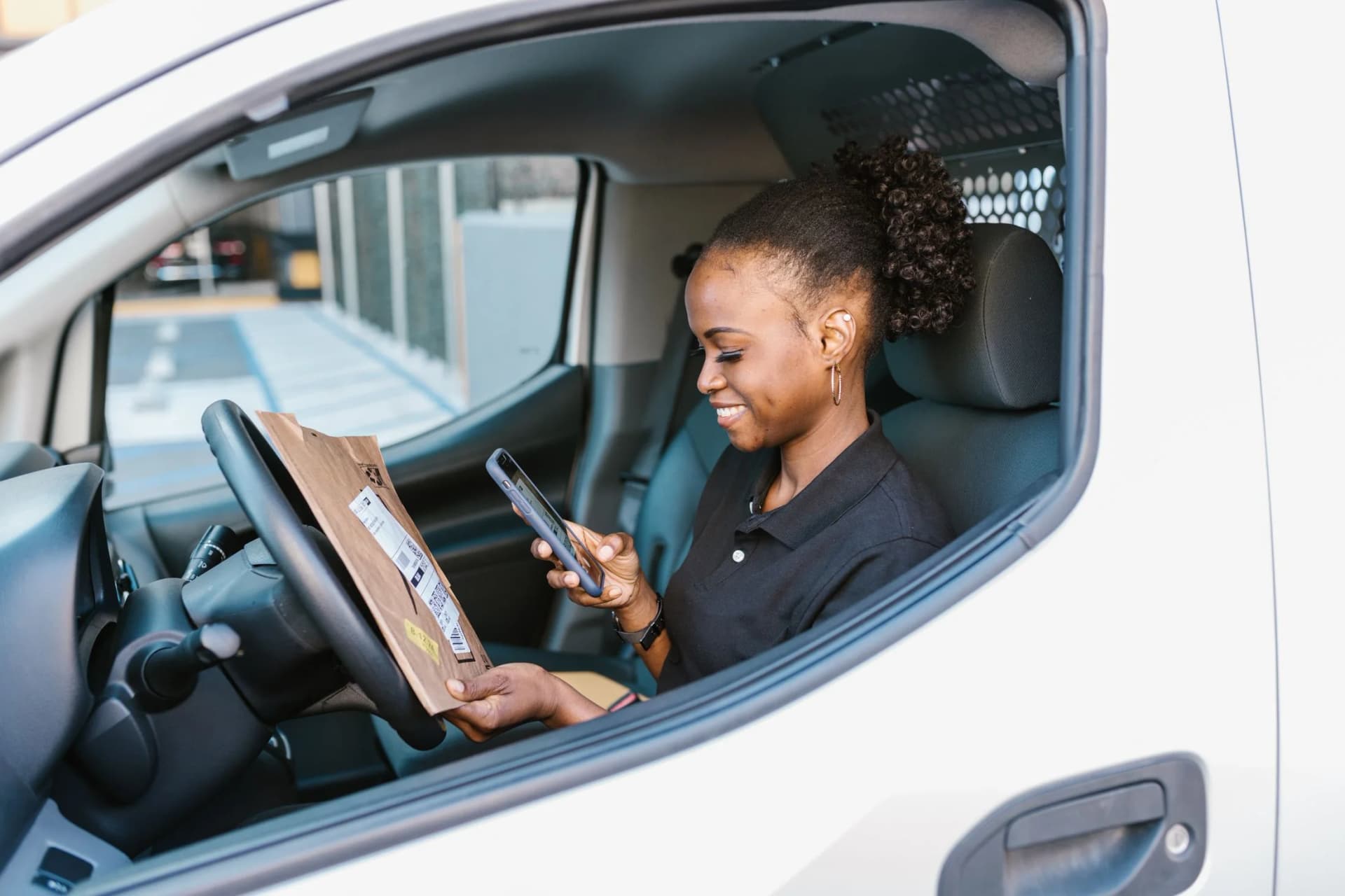 Lachende vrouw met een telefoon in een bestelbus