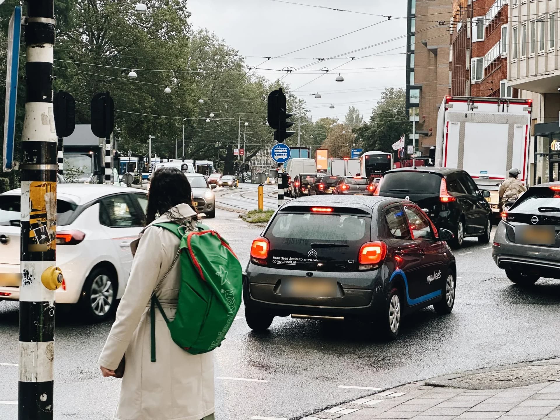 Vrouw wacht bij een druk kruispunt in de stad